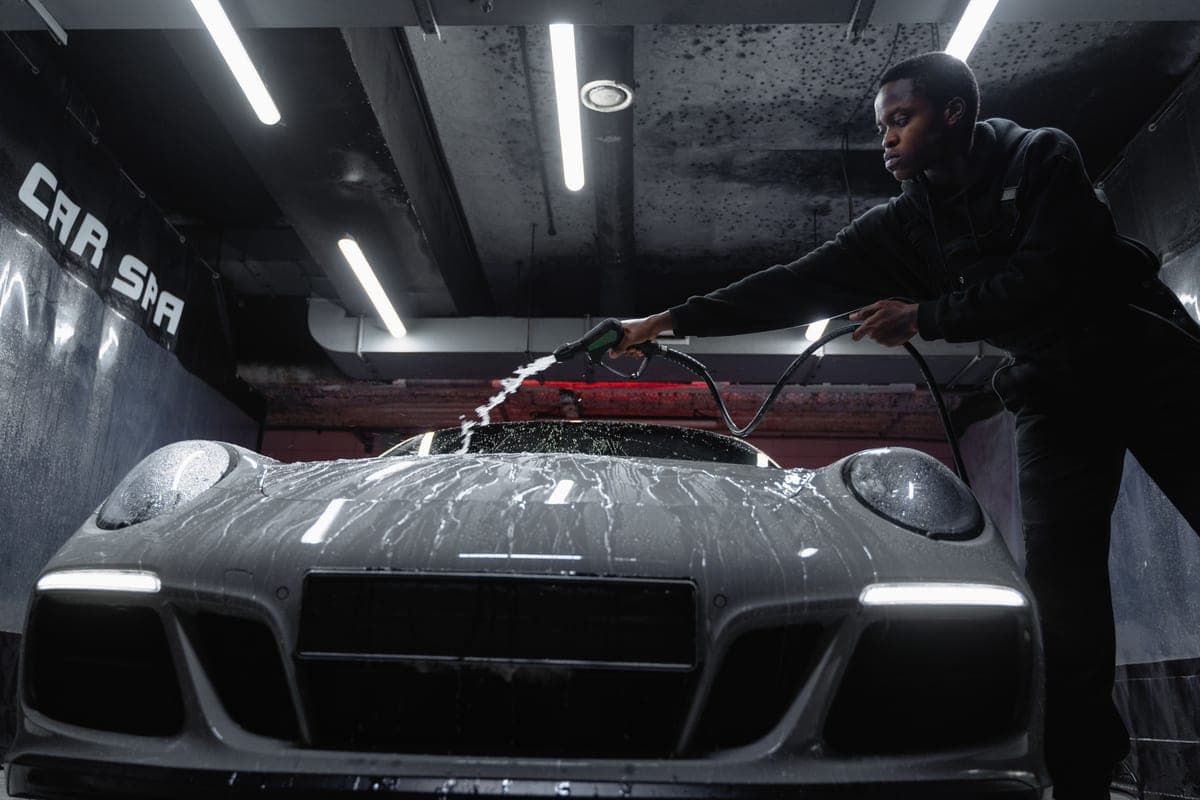 A car being detailed in a clean home garage with products on a bench