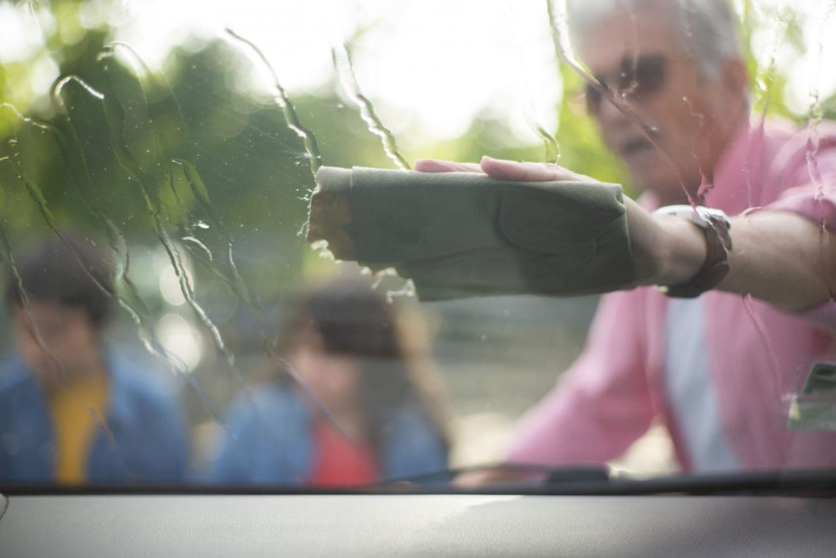 A streak-free car windshield being wiped with a clean microfiber towel