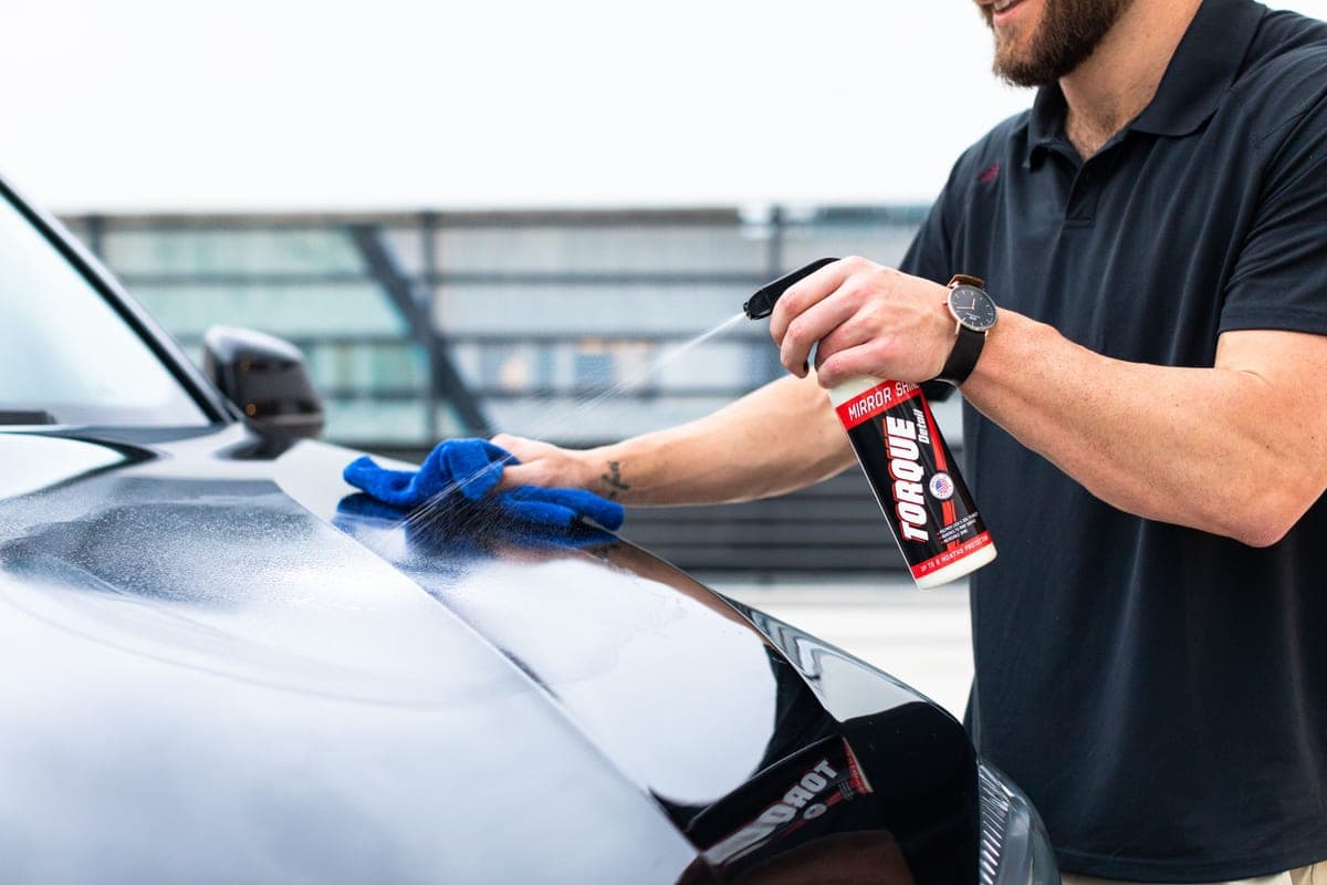 An assortment of car detailing bottles, brushes and microfiber towels laid out