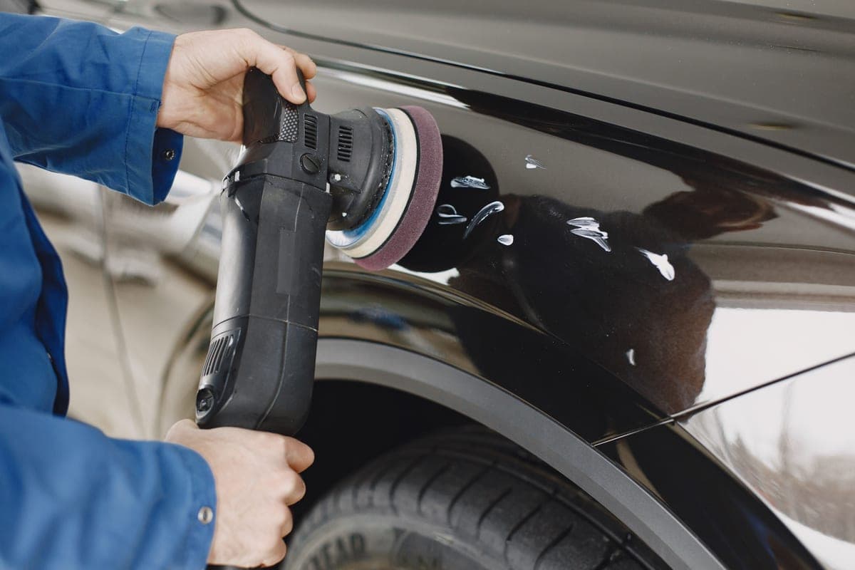 A dual-action polisher working compound across a car panel