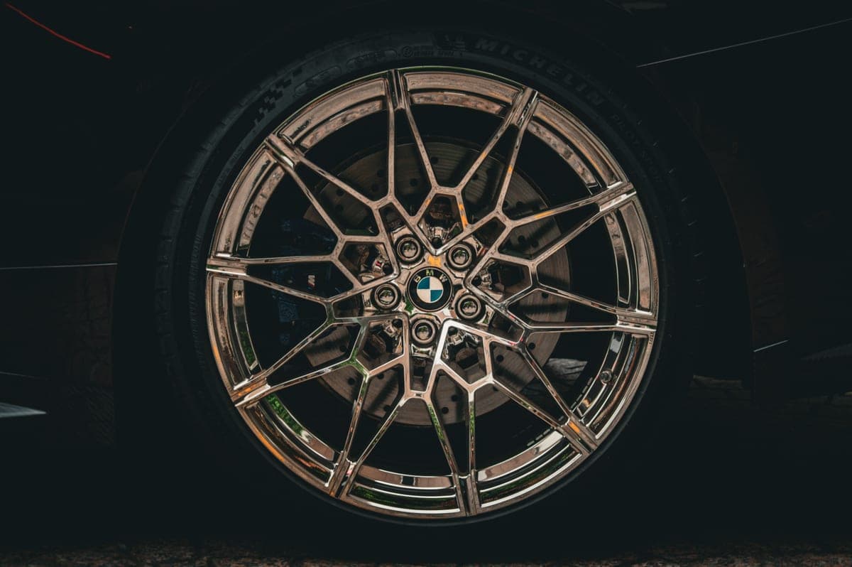 A clean alloy wheel being rinsed with a wheel brush nearby